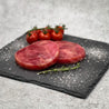 Yellowfin Tuna Burger Patty on slate with cherry tomatoes and herbs in Singapore.